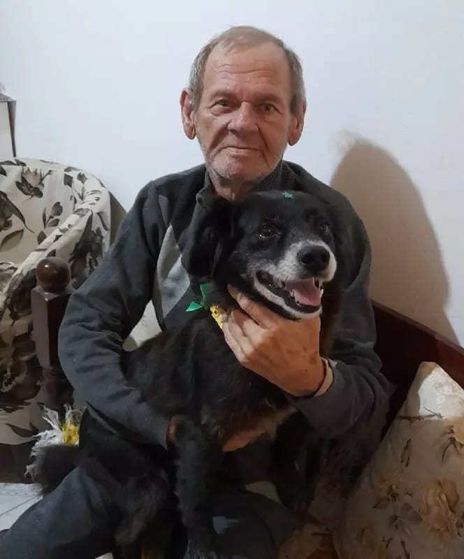 a-black-dog-in-the-arms-of-an-elderly-man